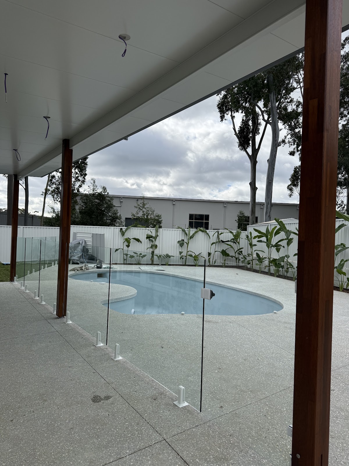 Frameless glass pool fence seen from under a patio roof