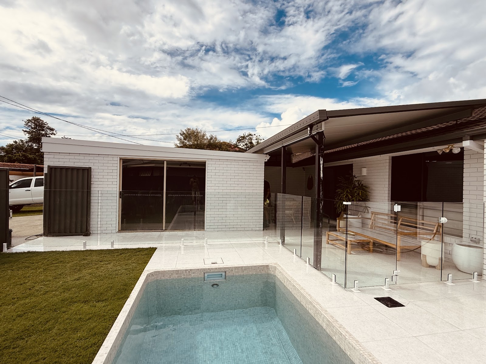 Plunge pool beside a white brick cabana, with a frameless glass fence enclosing the alfresco